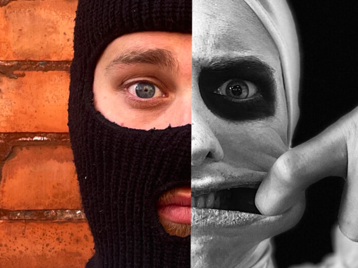 A close up photo of a face split down the middle; one half of the face is wearing a balaclava, the other half is a black and white image, their face has been painted a light colour with a dark circle around the eye. They are pulling the side of their mouth with their finger.